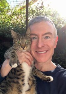 Man Holding a Tabby Cat Close to His Face Outdoors