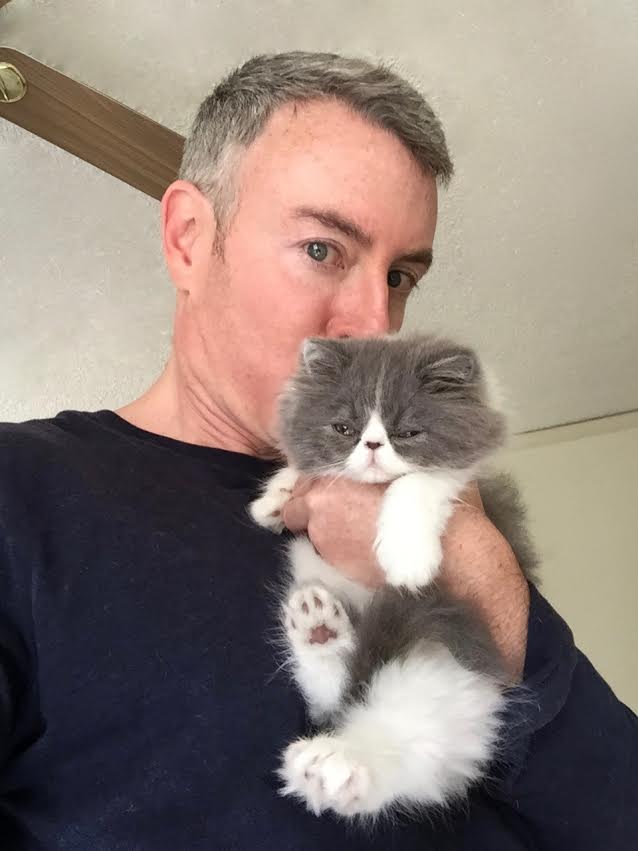 Man Holding a Gray Cat Close to His Face Indoors