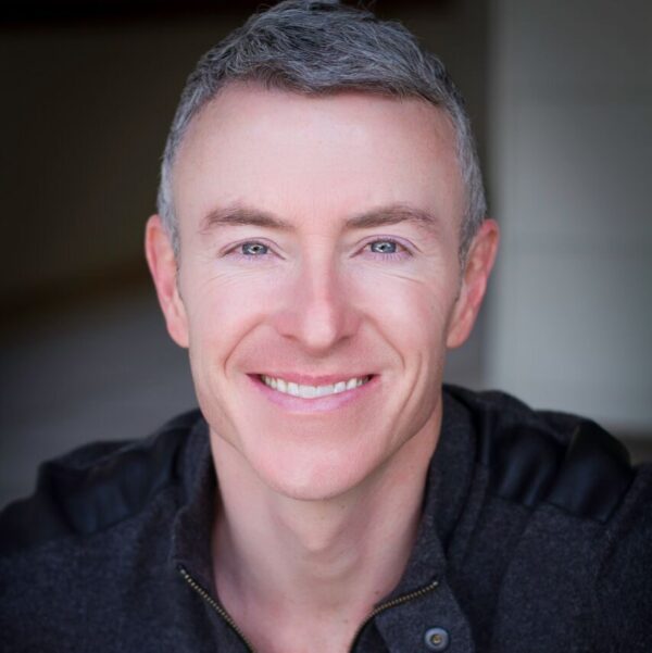 Professional Headshot of a Smiling Man Against a Dark Background