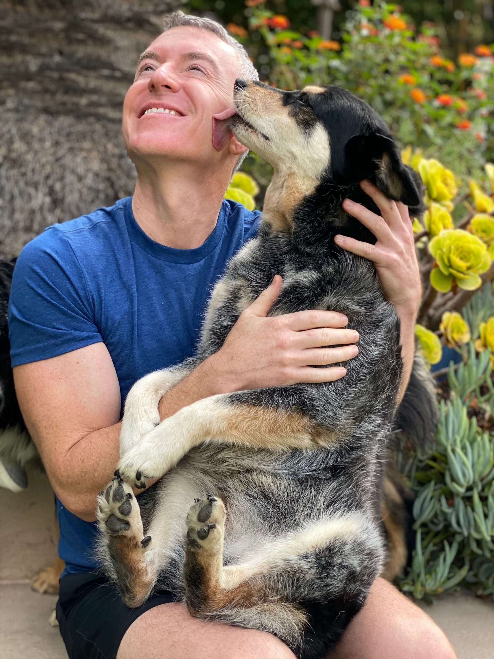 Michael R. Burke sharing a moment with a dog outdoors