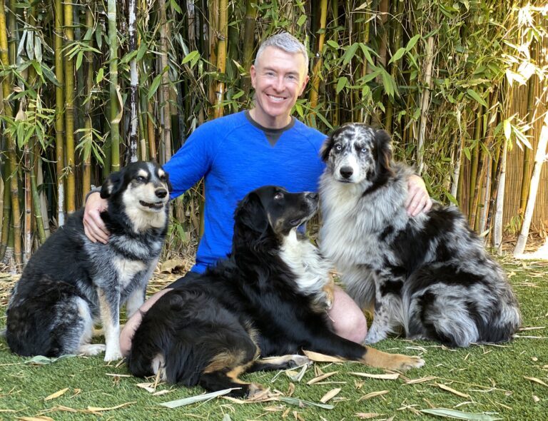 Michael R Burke sitting with dogs in bamboo garden