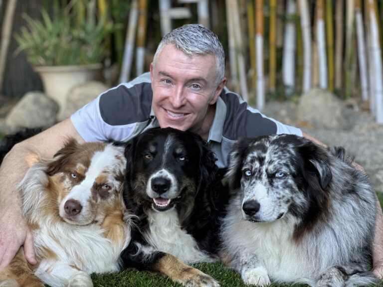 Michael R Burke sitting outdoor connecting with his dogs