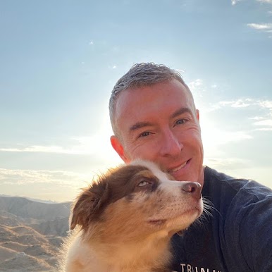 Michael R. Burke outdoors with a dog