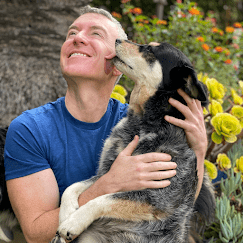 Michael R Burke happily outside with a dog