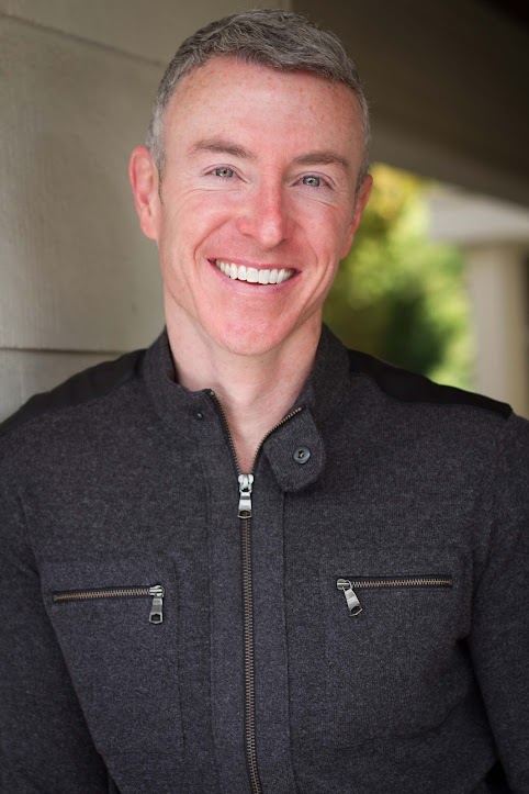 Professional Headshot of a Man Smiling Against a Neutral Background
