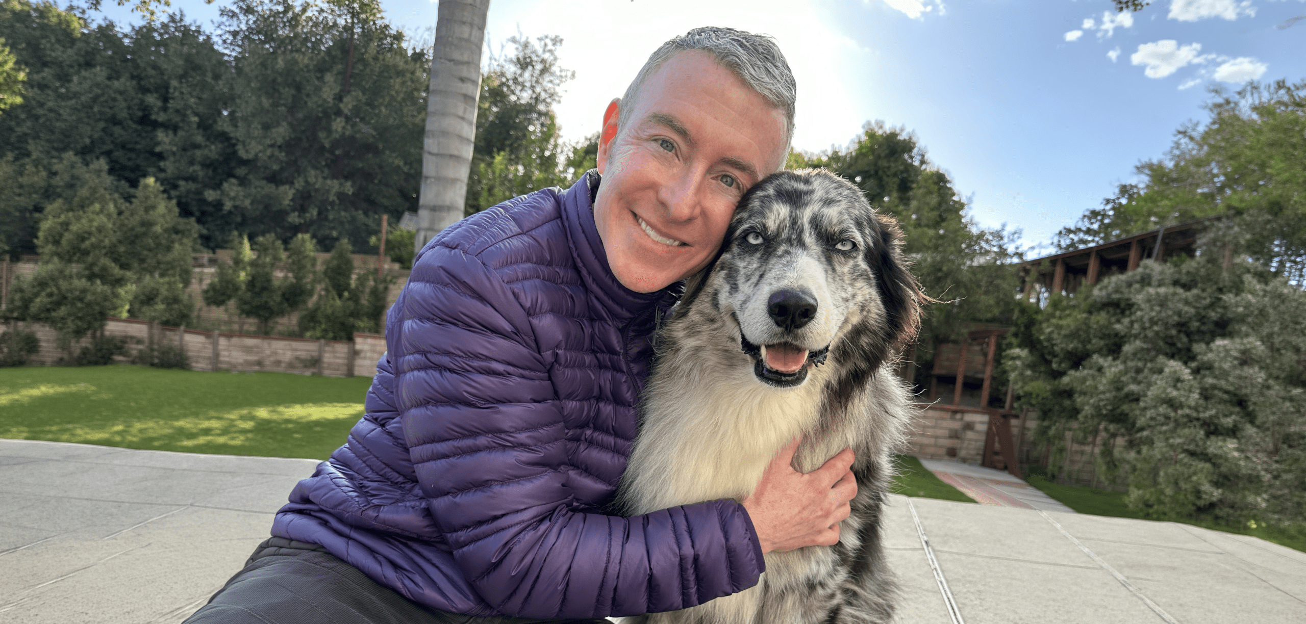 Man Hugging a Large Fluffy Dog While Smiling