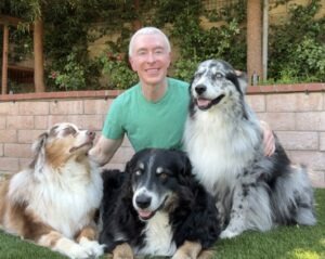 Animal communicator Michael R. Burke sitting outdoors with his three dogs